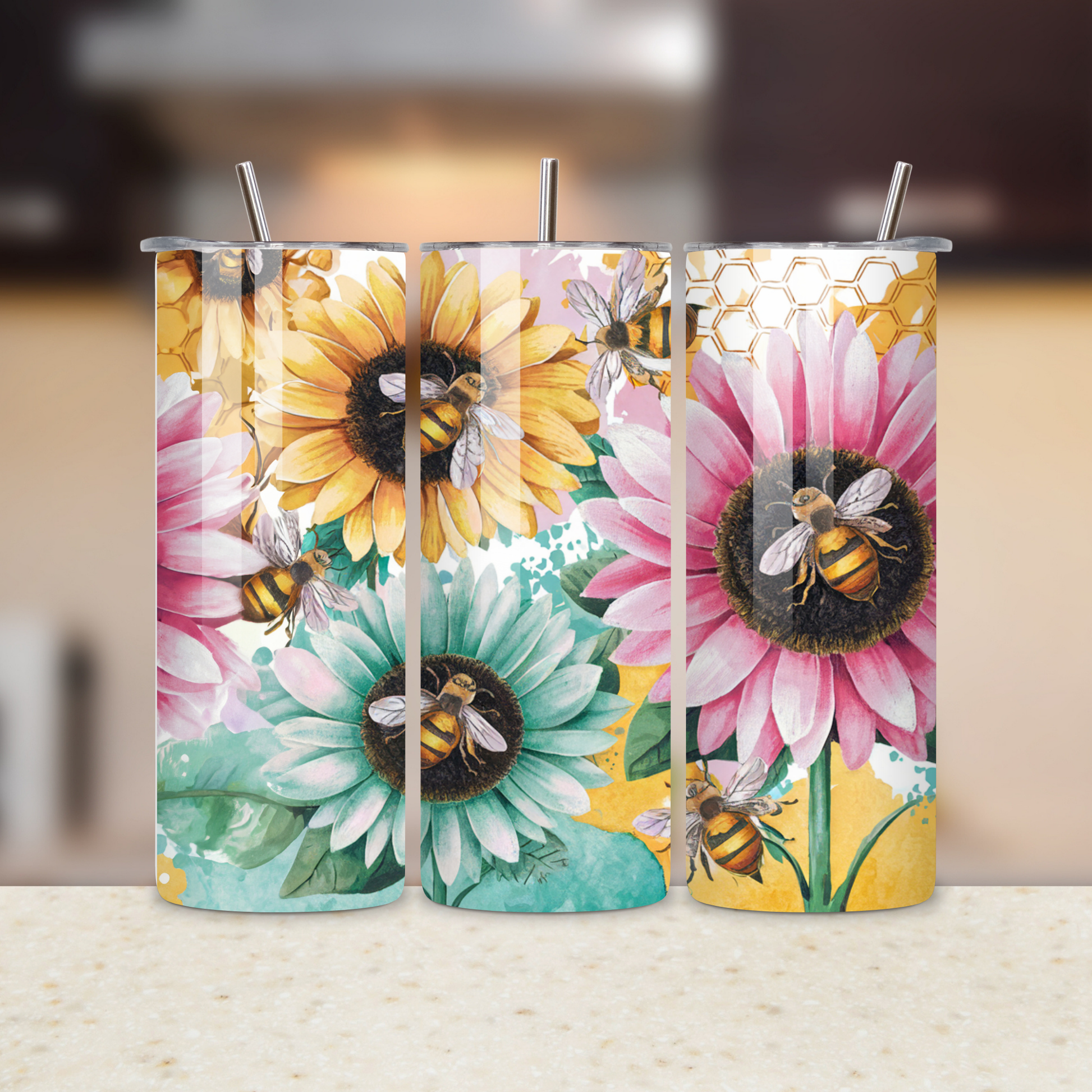 Three colorful tumblers with floral designs and bees on a blurred background