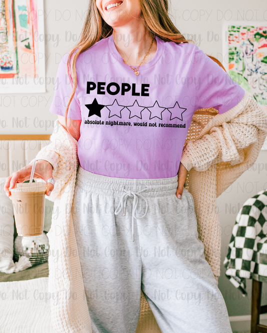 Person wearing a purple shirt with a humorous graphic and text, holding a drink.