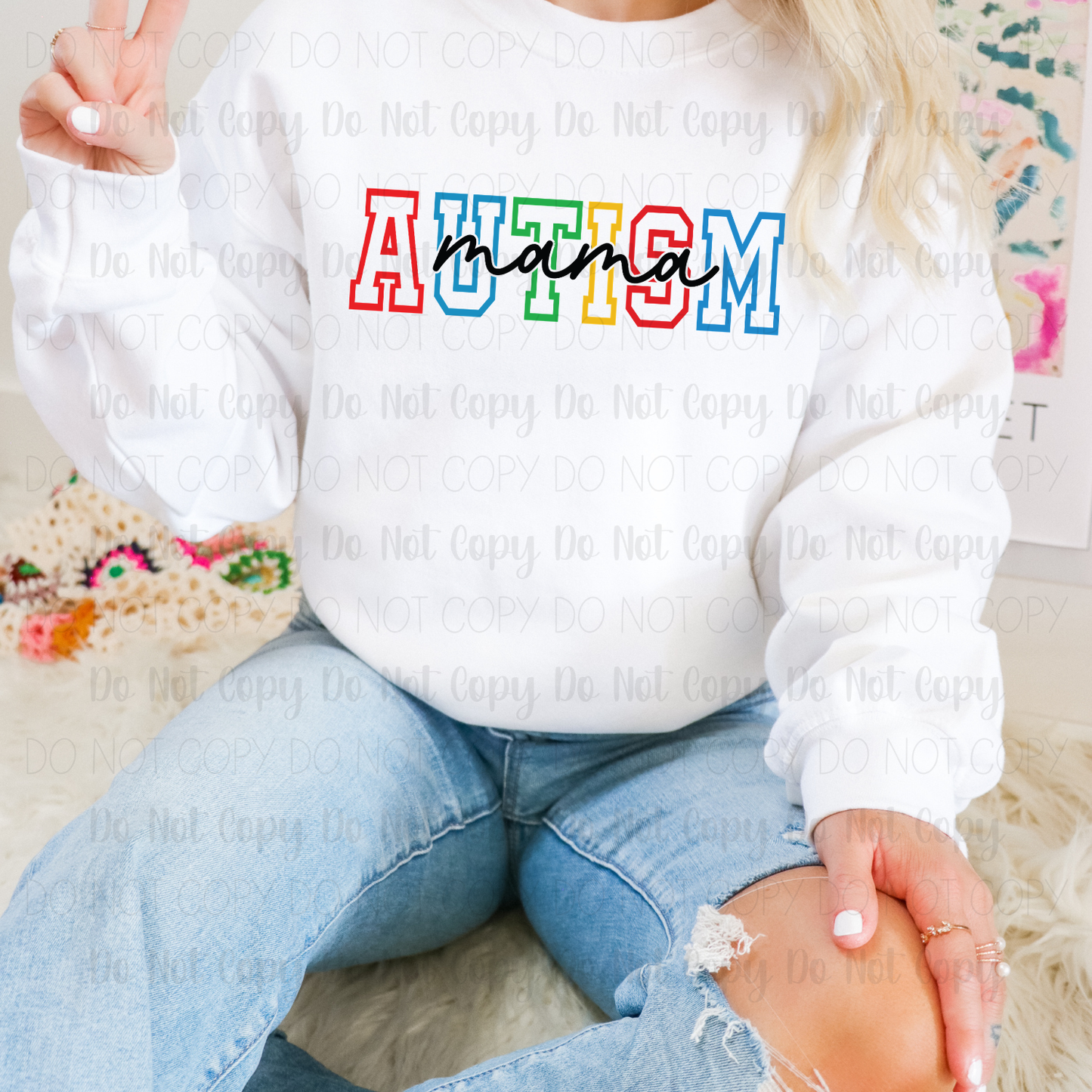 Person wearing a white sweatshirt with 'Autism Mama' in colorful letters.