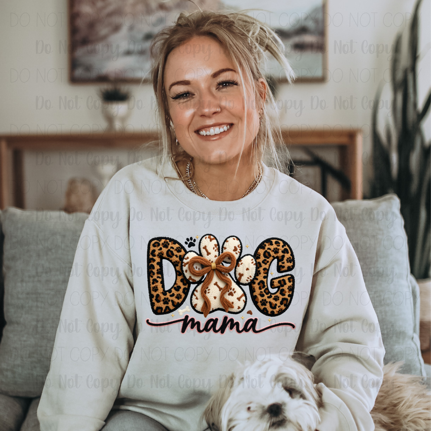 Woman wearing a sweatshirt with 'Dog Mama' text and leopard print design, sitting on a couch with a dog.