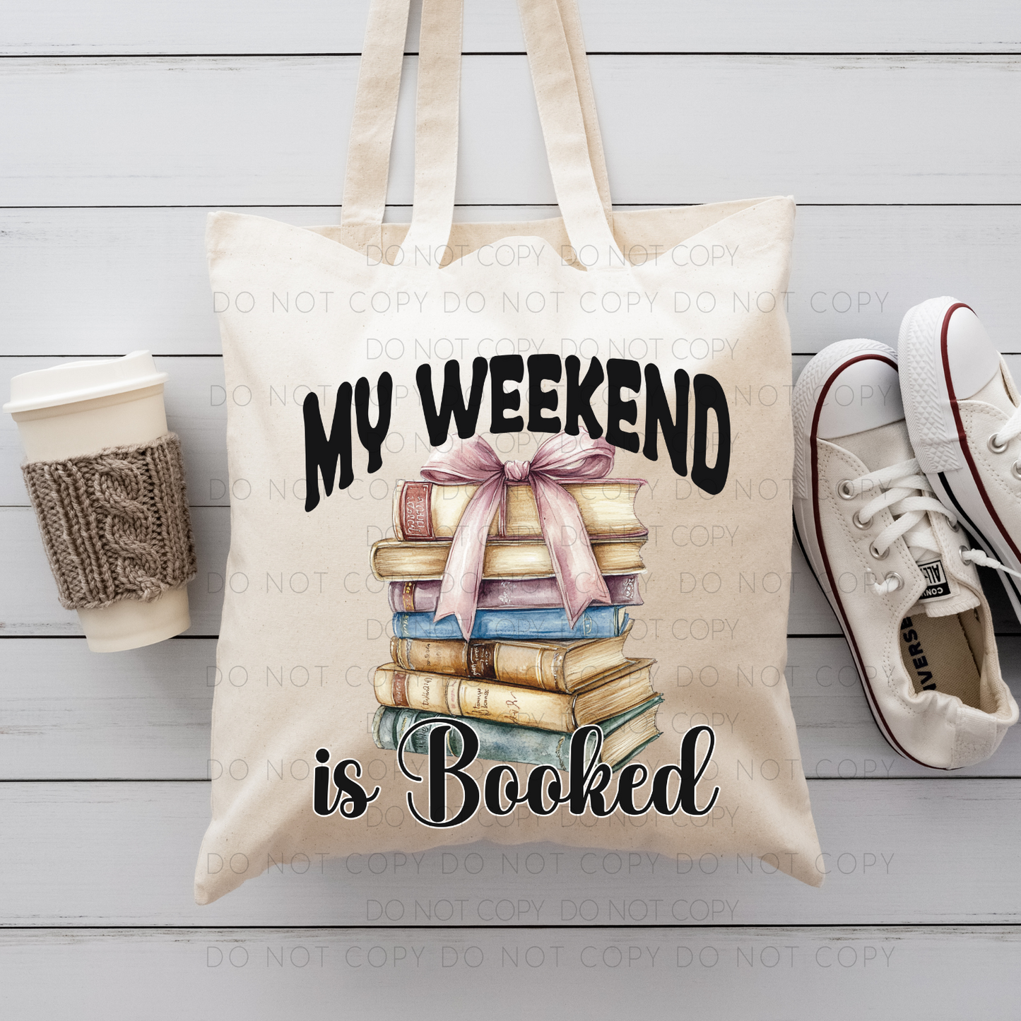 A beige cotton tote bag with 'My Weekend Is Booked' printed on it, featuring an illustration of stacked books, a bow, and a cup alongside.
