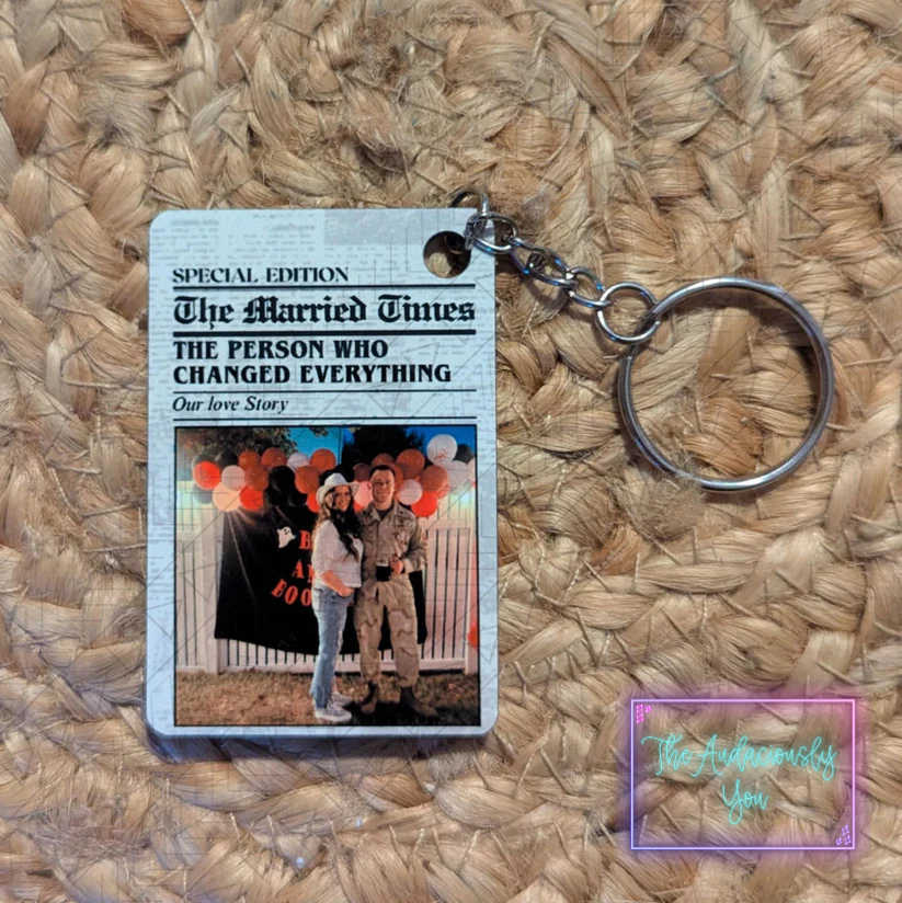 Keychain with a printed card featuring a couple and text on a woven surface