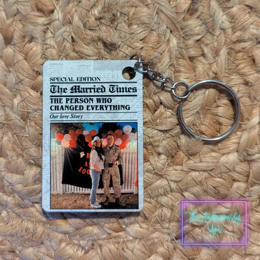 Keychain with a printed card featuring a couple and text on a woven surface
