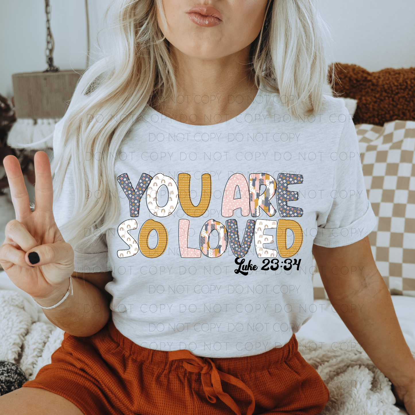 A person wearing a gray t-shirt with the text 'YOU ARE SO LOVED' printed on it, sitting on a couch.